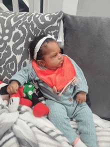 a baby wearing a bib sits on a couch