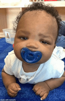 a baby with a pacifier in his mouth looks at the camera