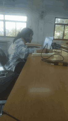 a woman sits at a desk with a laptop