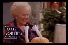 a woman holding a turkey with doris roberts as marie written on the bottom