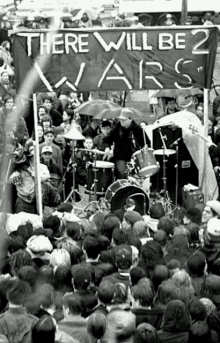 a crowd of people are gathered in front of a banner that says there will be 2 wars