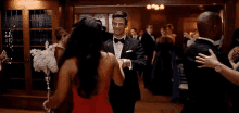 a man in a suit and bow tie is dancing with a woman in a red dress .