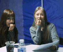 two women sit at a table with a bottle of water