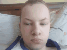 a young man laying on a bed with a blue and white shirt