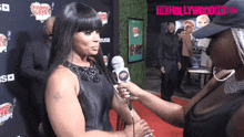 a woman is being interviewed on a red carpet in front of a sign that says " the hollywood film "