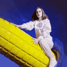 a woman is sitting on top of a yellow sculpture