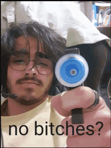 a man wearing glasses and a microphone is holding a toy gun with the words " no bitches " on the bottom