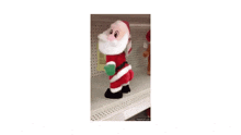 a stuffed santa claus is standing on a shelf