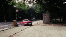 a red car is parked on the side of the road next to a bus stop with a sign that says no bikes