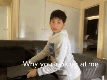 a boy sitting on a couch with a laptop and the words " why you looking at me "