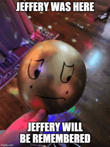 a person is holding a balloon with an angry face drawn on it and the caption jeffery was here