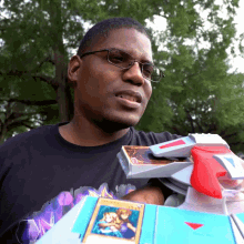 a man wearing glasses is holding a toy gun and a card with a picture of a child on it