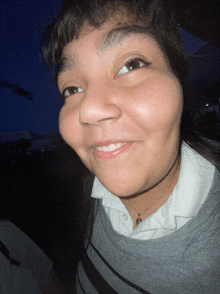 a girl wearing a white shirt and a necklace smiles for the camera