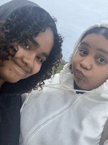 two girls with curly hair are posing for a picture together