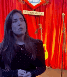 a woman is standing in front of a microphone in front of a red curtain and a metro sign .