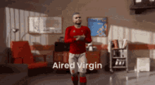 a man in a red shirt and white shorts is dancing in a room with the words aired virgin written on the bottom