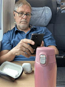 a man sits at a table looking at a cell phone