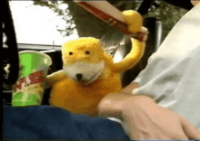 a person is holding a stuffed animal in their lap in a car with a max cup in the background