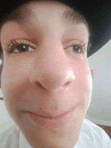 a close up of a young man 's face with a hat on