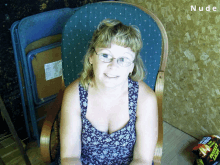 a woman wearing glasses sits in a chair with a bag of potato chips behind her