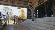 a man in a suit walks down a set of stairs in front of a building that says jayesh jewelers