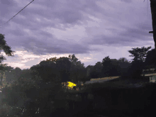 a purple sky with trees in the foreground and a house in the background