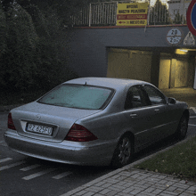 a silver car with a license plate that says rz 625fu parked in front of a garage