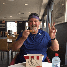 a man sitting at a table with a kfc box in front of him