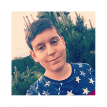 a young boy wearing an american flag shirt stands in front of a tree