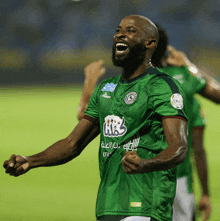 a soccer player wearing a green jersey that says ' a & a ' on it