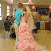 a man in a blue shirt is dancing with a woman in a pink dress in front of a france banner