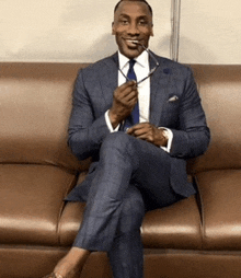 a man in a suit and tie is sitting on a couch with his legs crossed