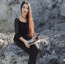 a woman sitting on a rock holding a book that says ' i love you '