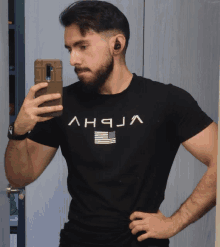 a man taking a picture of himself in a mirror with a shirt that says alpha on it