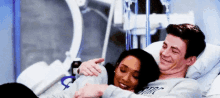 a man and a woman are laying in a hospital bed and hugging .