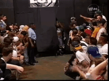 a crowd of people are sitting in a room watching a wrestler .