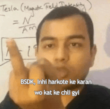 a man is giving the middle finger in front of a white board that says tesla magnetic field intensity