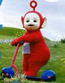 a teletubbies character is riding a scooter in the grass .