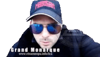 a man wearing sunglasses and a hat with the name grand monarque on it