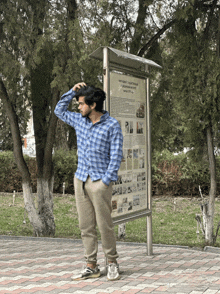 a man in a blue plaid shirt is standing in front of a sign that says ' historical monuments ' on it