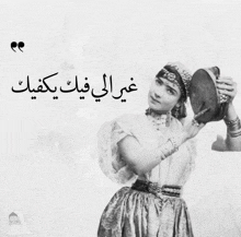 a black and white photo of a woman holding a drum with arabic writing on it