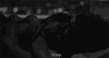 a black and white photo of a man and woman kissing with the words " stay " above them