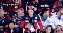 a group of people are sitting in a stadium and one of them is wearing a hat that says canada