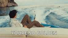 a man is laying on a boat in the ocean with the words " youre so golden " behind him