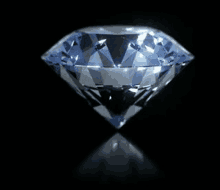 a diamond is sitting on a black surface with a reflection .