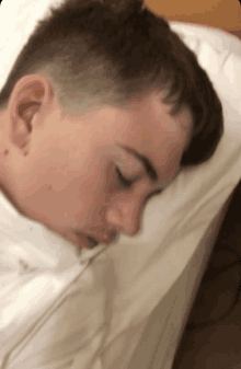 a young boy is sleeping on a bed with a white pillow