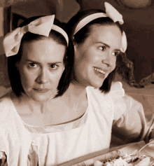 two women wearing white headbands with bows on them