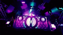 a dj stands in front of a stage with a purple light behind him