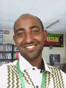 a man is smiling in front of a sign that says come into