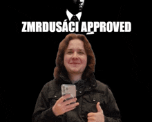 a man in a black jacket is giving a thumbs up in front of a black background that says zmrzusaci approved